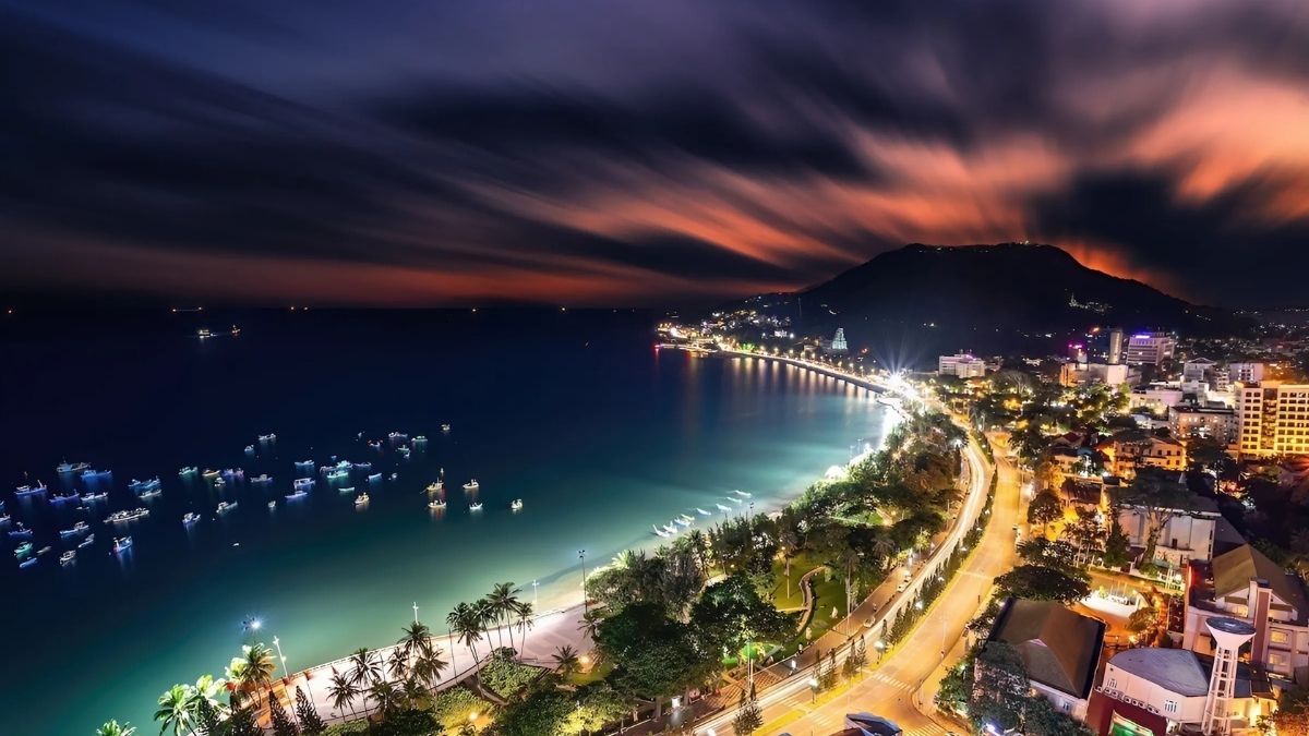 Bờ biển Vũng Tàu về đêm với cung đường ven biển, hàng dừa và núi phía xa